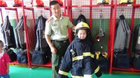 “我是小小消防员”主题活动，小朋友们在消防员叔叔的帮助下穿上消防衣。